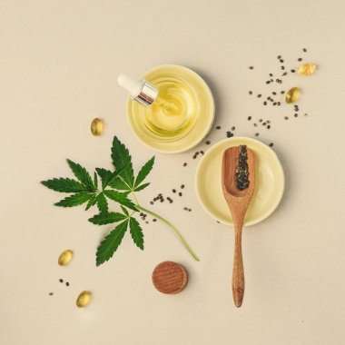 CBD yağı, bej arka planda marihuana yapraklı tentür. Kenevir tohumları