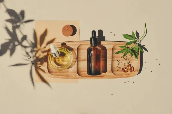 CBD yağı, kenevir tentürü bej arka planda kenevir yapraklı pipetle