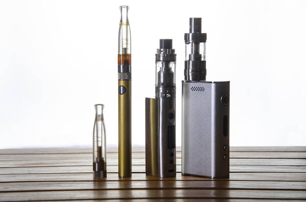 Popular vaping e cig devices mod.electronic cigarette over a wooden background. vaporizer e-cig old device model. 