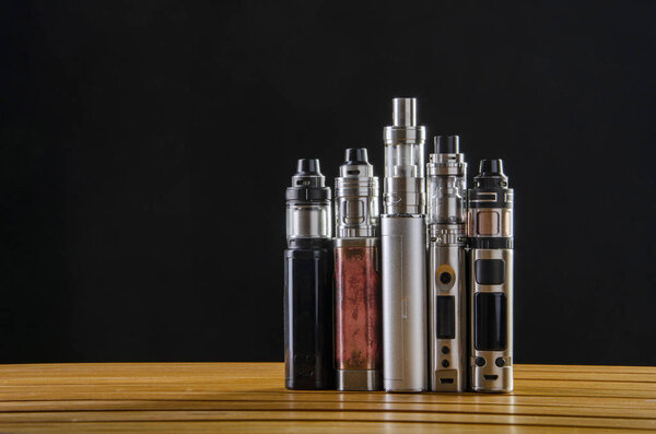 Popular vaping e cig devices mod.electronic cigarette over a wooden background. vaporizer e-cig old device model. 