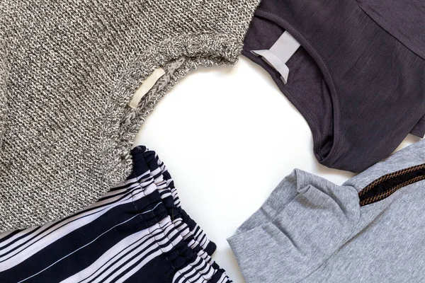 Pile of grey clothing in a flat lay with round copy space in the middle