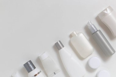 Işık arkaplanındaki kozmetik kavanozlar metin için fotokopi alanı ile çapraz konumda. Tek renkli beyaz ve gri şişeler.