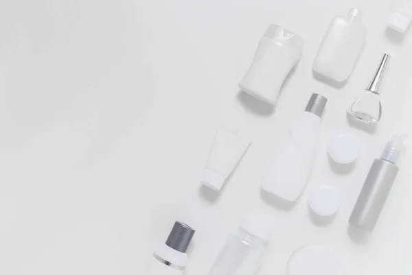 Işık arkaplanındaki kozmetik kavanozlar metin için fotokopi alanı ile çapraz konumda. Tek renkli beyaz ve gri şişeler.