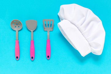 Mavi arka planda beyaz aşçı şapkası ve oyuncak oyuncakları. Çocuklar yemek yapma konsepti