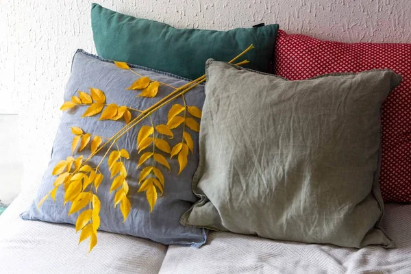 Mevsimlik dekorasyon için sarı yapraklı kanepede üç yastık. Sonbahar iç mimarisi 