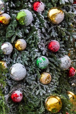 Noel ağacı süslemeleri. Kırmızı ve altın topları, oyuncakları ve ışıkları sallanan yeşil ladin çalıları.