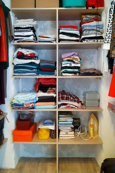 Large wardrobe closet  with neatly folded different clothes, home stuff and boxes. Space organization concept, organizers and cleanliness in the house