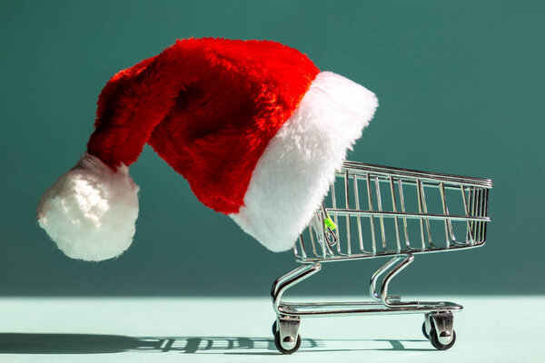 Shopping cart in a santa hat. Christmas and New Year shopping sale concept