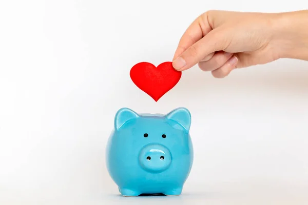 Kırmızı kalbi kumbaraya koyuyor. Aşkı güvende tutma ve ilişkiye yatırım yapma kavramı. 