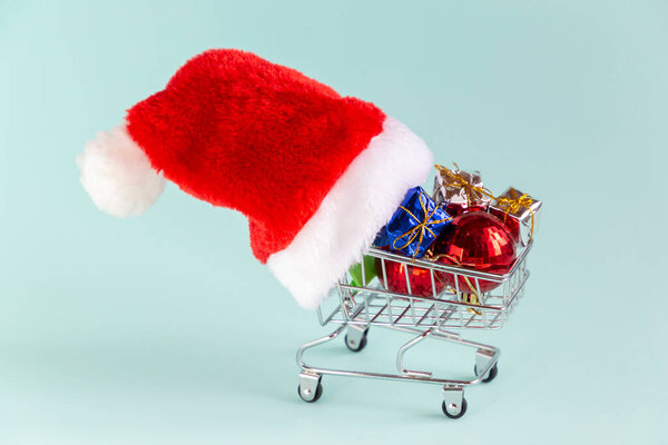 Shopping cart full of gifts in a santa hat. New year and christmas winter sale concept