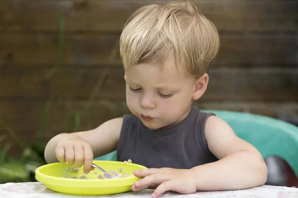 Счастливый милый малыш, который ест кашу ложкой — стоковое фото