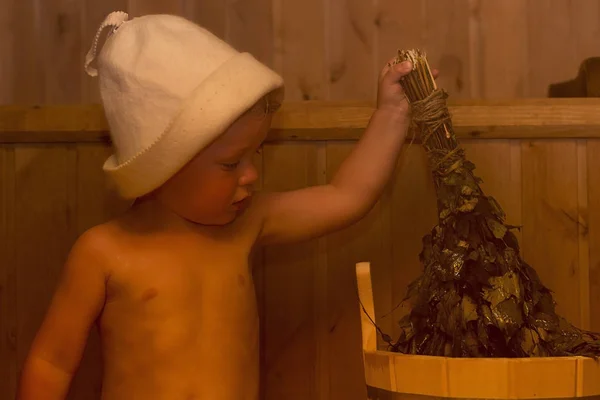 Schönheit, Gesundheit. Babyboy entspannt in der Sauna Kleinkind mit Besen und Hut in der russischen Sauna oder Badewanne — Stockfoto