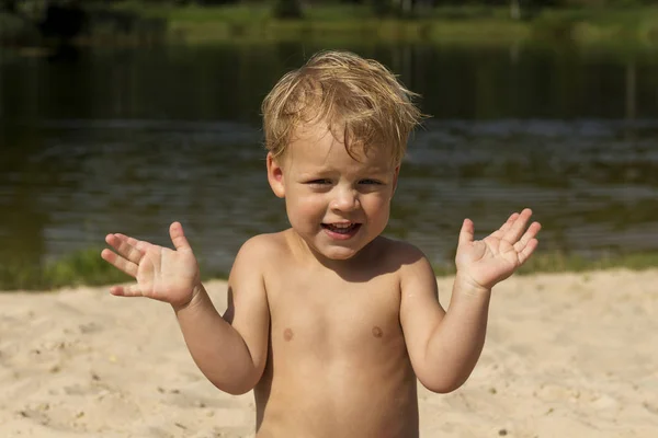 Χαριτωμένο μωρό αγόρι που παρουσιάζουν για μια φωτογράφηση. Πρόσωπο έκπληξη. Αστείο, μικρό παιδί στην παραλία — Φωτογραφία Αρχείου