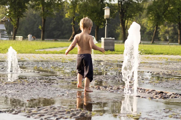 Мальчик играет в фонтане. Концепция счастья и беззаботного детства — стоковое фото