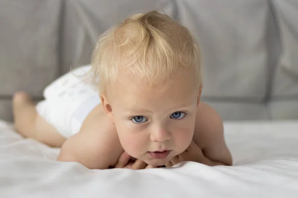 Lindo niño feliz en pañal acostado y jugando en la cama —  Fotos de Stock