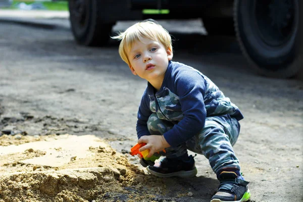 Маленький мальчик играет с игрушечной машиной на песке — стоковое фото