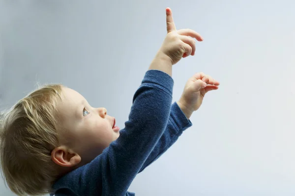 Beautiful blonde toddler looking up. Boy showing, kid holding his hand up. Copy space — Stock Photo, Image