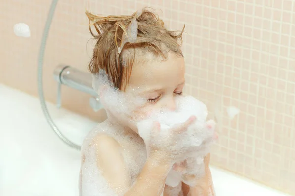 Nahaufnahme Gesicht des entzückenden Kleinkindes, das ein Bad mit viel Schaum in der Badewanne nimmt, fröhlicher netter kleiner Junge, der im Badezimmer spielt, Gesundheitskonzept für Kinder — Stockfoto