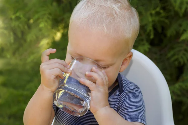 Портрет мальчика, пьющего стакан воды. Фотография на открытом воздухе — стоковое фото