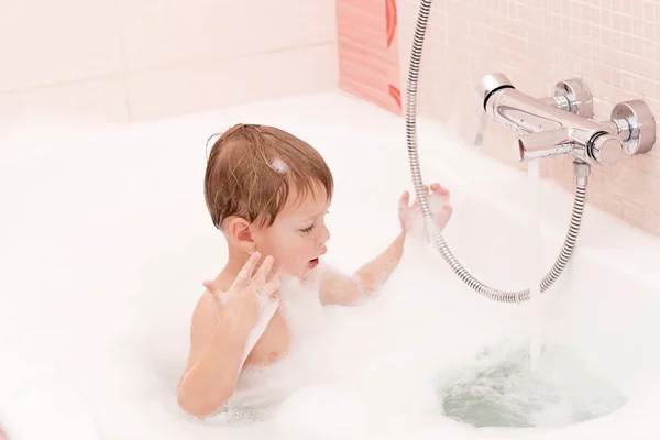 Funny little baby boy playing with foam in a bath tub — Stock Photo, Image
