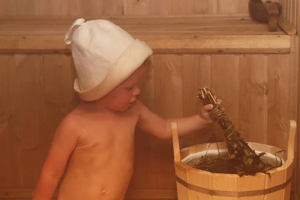 Краса, охорони здоров'я. Baby Boy розслаблююча сауна малюка з мітлою і капелюх у російських сауні або лазні. — стокове фото