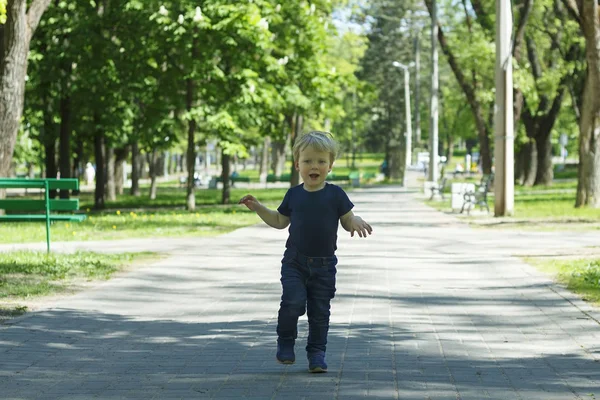 Toddler śmieszne bieganie i skakanie w wiosną lub jesienią aleja. — Zdjęcie stockowe
