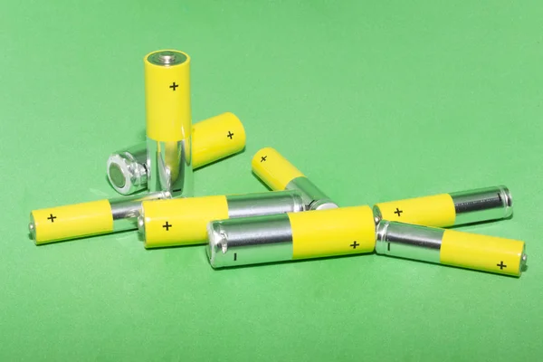 AA batteries on green background. Concept of recycling — Stock Photo, Image