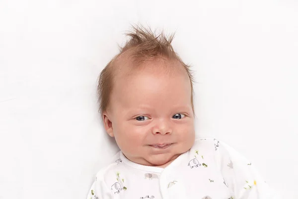 Recém-nascido bonito está sorrindo no tapete branco. Adorável menino olhando para a câmera — Fotografia de Stock