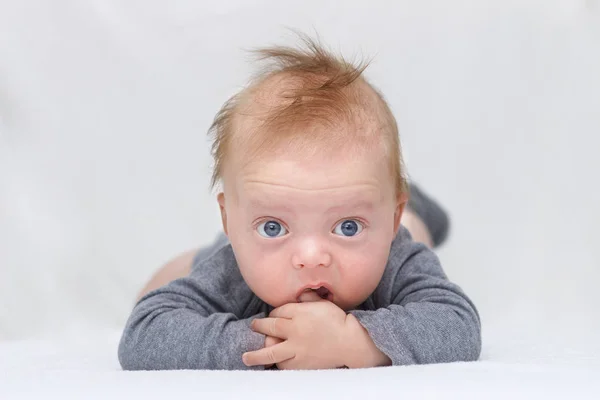 Bonito azul de olhos felizes bebê menino deitado na barriga e olhando para espaço de cópia da câmera — Fotografia de Stock