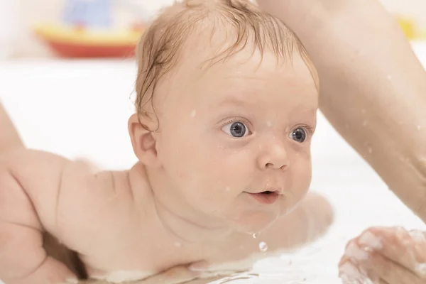 Маленький хлопчик з блакитними очима приймає ванну у ванну — стокове фото