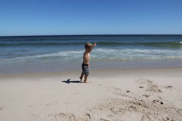 一个金发小男孩独自走在海洋的海岸上，没有父母。夏天， 热， 海， 太阳， 海滩. — 图库照片