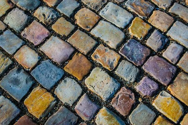 Typical colorful cobblestone street, sidewalk made of red, yellow, orange, grey, blue, purple and white rectangular pieces of stone, top view, european city