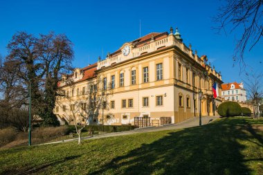 Prague, Çek Cumhuriyeti / Avrupa - 31 Ocak 2019: eski kale Liben, Prag, şimdi bir koltuk Belediye, duvar saati, sarı cephe, kırmızı çatı, Çek bayrak, yeşil çimen, parke, güneşli bir gün