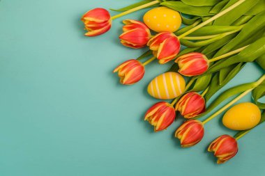 Bir sürü güzel taze kırmızı ve Sarı Lale çiçek yeşil yaprakları ve Paskalya yumurtaları ile yerleştirilen turkuaz arka plan, kopya alanı, üstten görünüm, Bahar düz düzen dekorasyon 