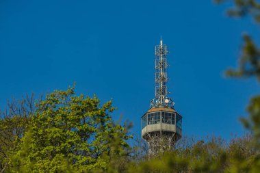 Prag, Çek Cumhuriyeti / Avrupa - 22 Nisan 2019: Güneşli bir bahar gününde Eyfel kulesini andıran 1891 yılında inşa edilmiş ünlü bir gözetleme kulesi olan Petrin kulesinin detayları. Berrak mavi gökyüzü, ön planda yeşil ağaçlar.