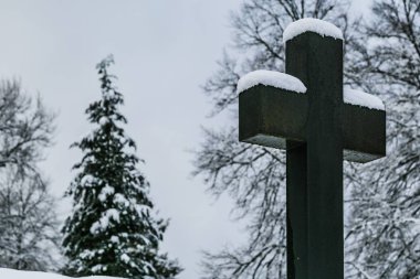 Hıristiyan taşının mezarlıkta kesiştiği kış sahnesi ve arka planda karla kaplı ağaçlar..