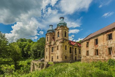Skoky, Zlutice / Çek Cumhuriyeti - 21 Haziran 2019: Skoky, Maria Stock'taki Meryem Ana Ziyareti barok kilisesi, Batı Bohemya'da eski bir hac yeridir. Güneşli bir gün, bulutlarla dolu mavi gökyüzü. Eski evin harabesi. Yeşil çimen.