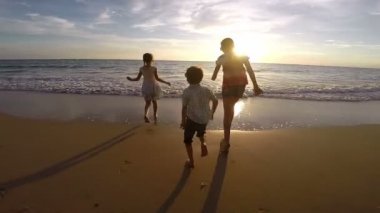 Mutlu çocuk sahilde günbatımı anda oynamak. Mutlu dostu aile kavramı.