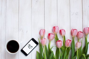 Bir fincan sade kahve, telefon ve pembe laleler