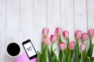 Bir fincan sade kahve, telefon ve pembe laleler