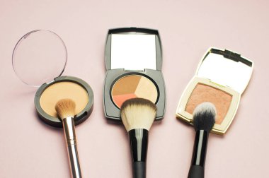 Pembe bir arka plan üzerinde renkli kozmetik toz allık düzeltici Fırçalar ayarlayın. Makyaj Aksesuarları üst görünümü