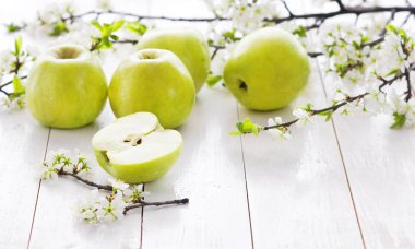 Olgun yeşil elma ile bahar çiçekleri Beyaz ahşap zemin üzerinde. Hafif yiyecekler arka plan, taze meyve, elma