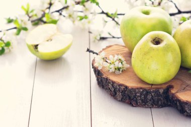 Olgun yeşil elma ile bahar çiçekleri Beyaz ahşap zemin üzerinde. Hafif yiyecekler arka plan, taze meyve, elma