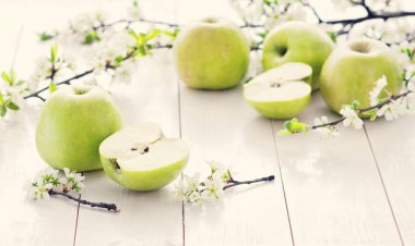 Olgun yeşil elma ile bahar çiçekleri Beyaz ahşap zemin üzerinde. Hafif yiyecekler arka plan, taze meyve, elma