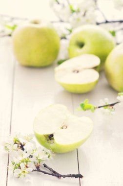 Olgun yeşil elma ile bahar çiçekleri Beyaz ahşap zemin üzerinde. Hafif yiyecekler arka plan, taze meyve, elma