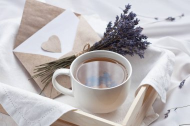 Bir tepsi ile bir fincan sıcak çay ve lavanta aşk mektubu yatakta. Bitkisel çay sıcak içmek ruh aşk mesajı kahvaltı sabah yaşam tarzı yatakta