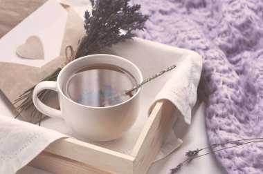Bir tepsi ile bir fincan sıcak çay ve lavanta aşk mektubu yatakta. Bitkisel çay sıcak içmek ruh aşk mesajı kahvaltı sabah yaşam tarzı yatakta