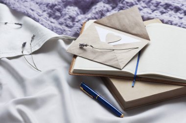 Not defteri mektup ve yatakta beyaz Tekstil ekose ve lavanta ile kitap. Günlük zarf yaşam tarzı şal eşarp lavanta rahat arka plan