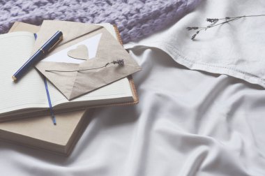 Not defteri mektup ve yatakta beyaz Tekstil ekose ve lavanta ile kitap. Günlük zarf yaşam tarzı şal eşarp lavanta rahat arka plan