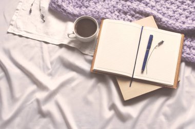 Not defteri bir fincan kahve ve bej tonlama ile bir kitap var. Günlük yaşam tarzı şal eşarp lavanta tonlama rahat arka plan